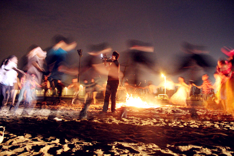 大家一起围着篝火跳“锅庄舞”，中间有人摔倒，有人光脚跳，有人拍照，有人当观众……