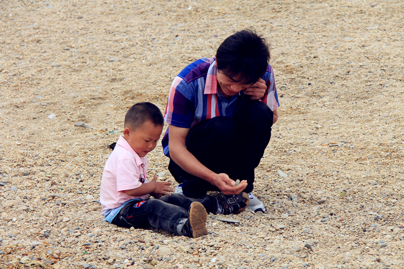 在付家庄公园海边看到的一位父亲和小孩在玩捡石子，让我回想起小时候我们拿碎裂的瓦片做的石子，回忆是个美好的东西。